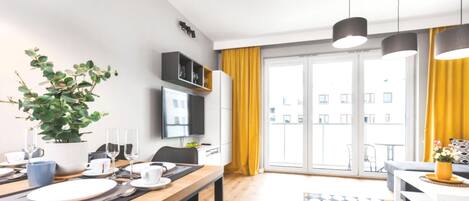 Una sala de estar moderna con comedor, ventanas amplias y vista a edificios.