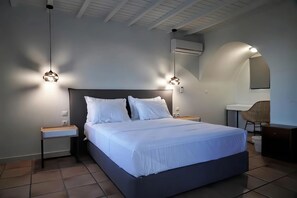 Un dormitorio moderno con una cama grande, mesitas de noche, un escritorio y una silla.