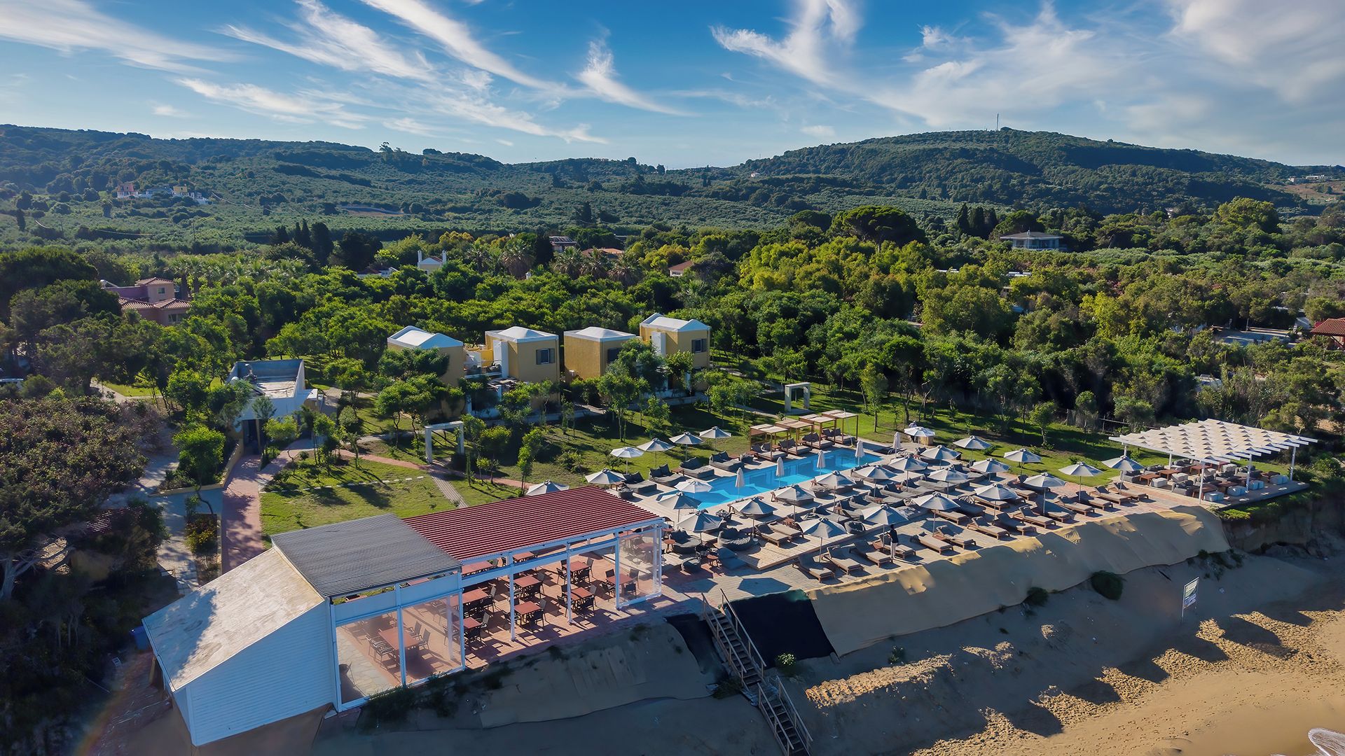 Un complexe hôtelier doté d’une piscine, d’un espace extérieur aménagé et offrant une vue sur les collines environnantes.