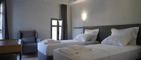 Ein Hotelzimmer mit zwei Betten, einem Schreibtisch, einem Stuhl und einem Fenster.