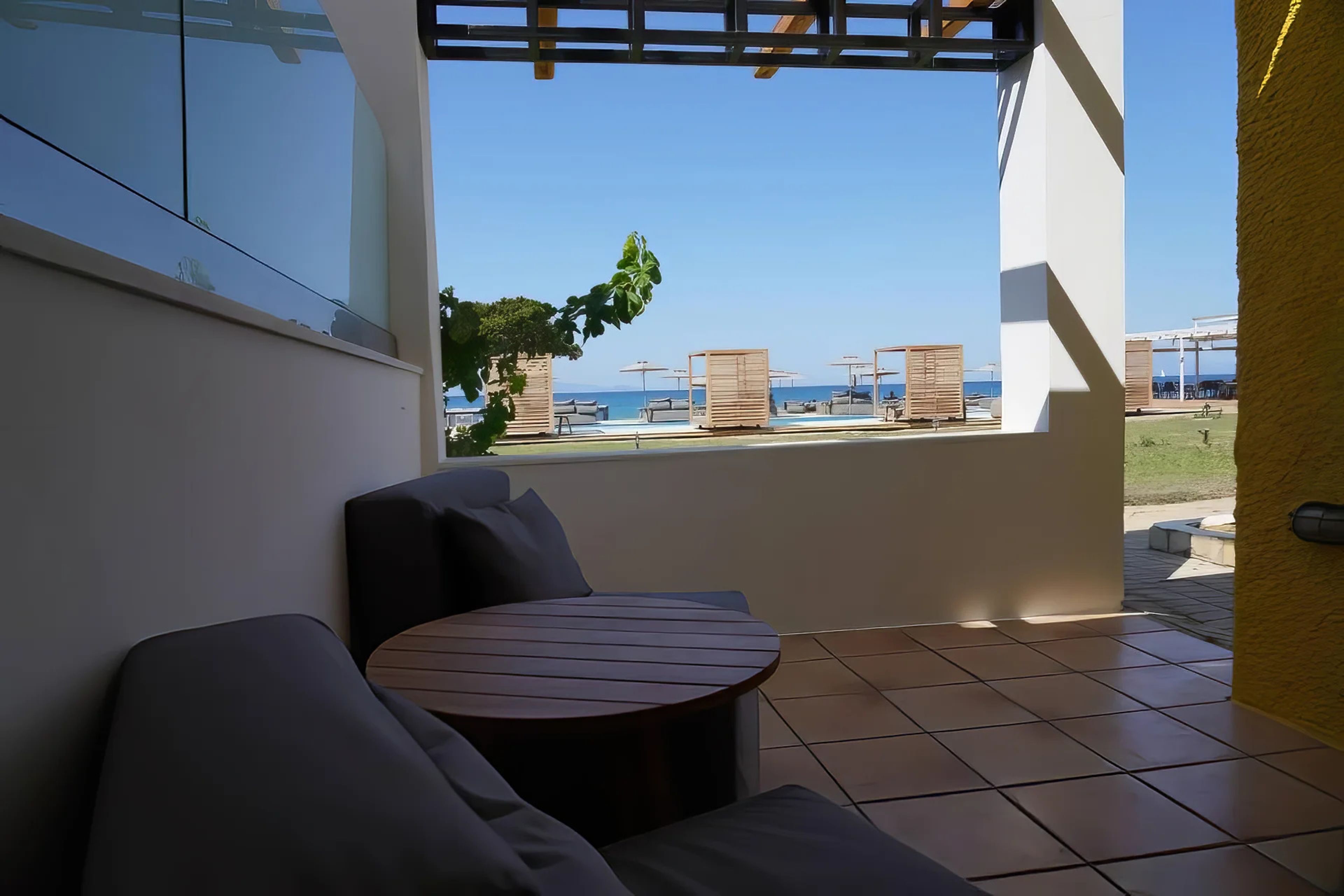Un balcón con vista al mar, una mesa redonda y un área de descanso.