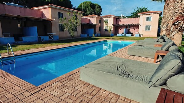 Una piscina con sillones de descanso y un patio de ladrillo.