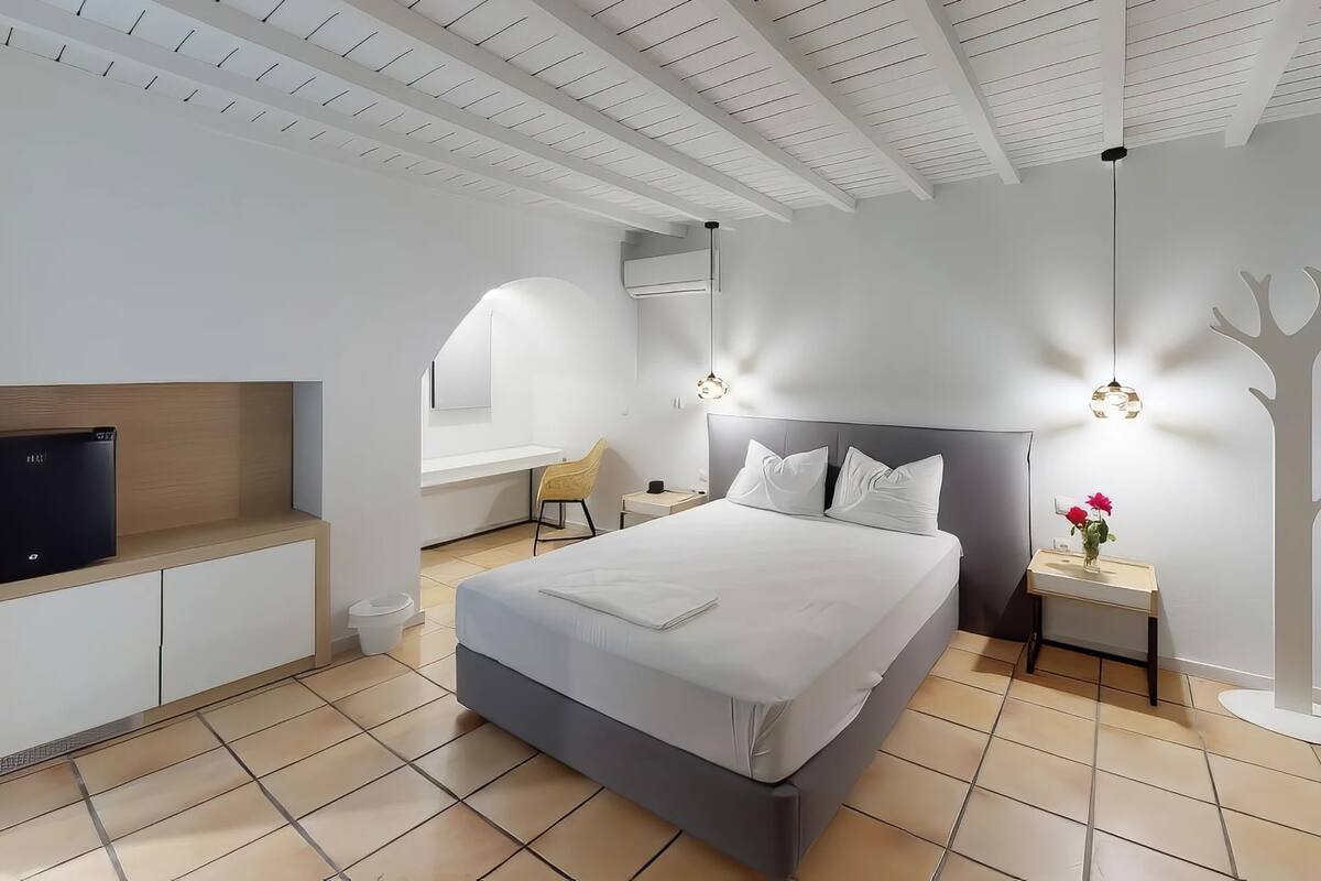A modern bedroom with a bed, bedside tables, a TV, and a unique tree-shaped wall decoration.