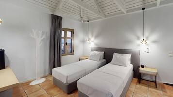 Habitación de hotel con dos camas individuales, un escritorio, una lámpara de pie y un ventanal con cortinas.