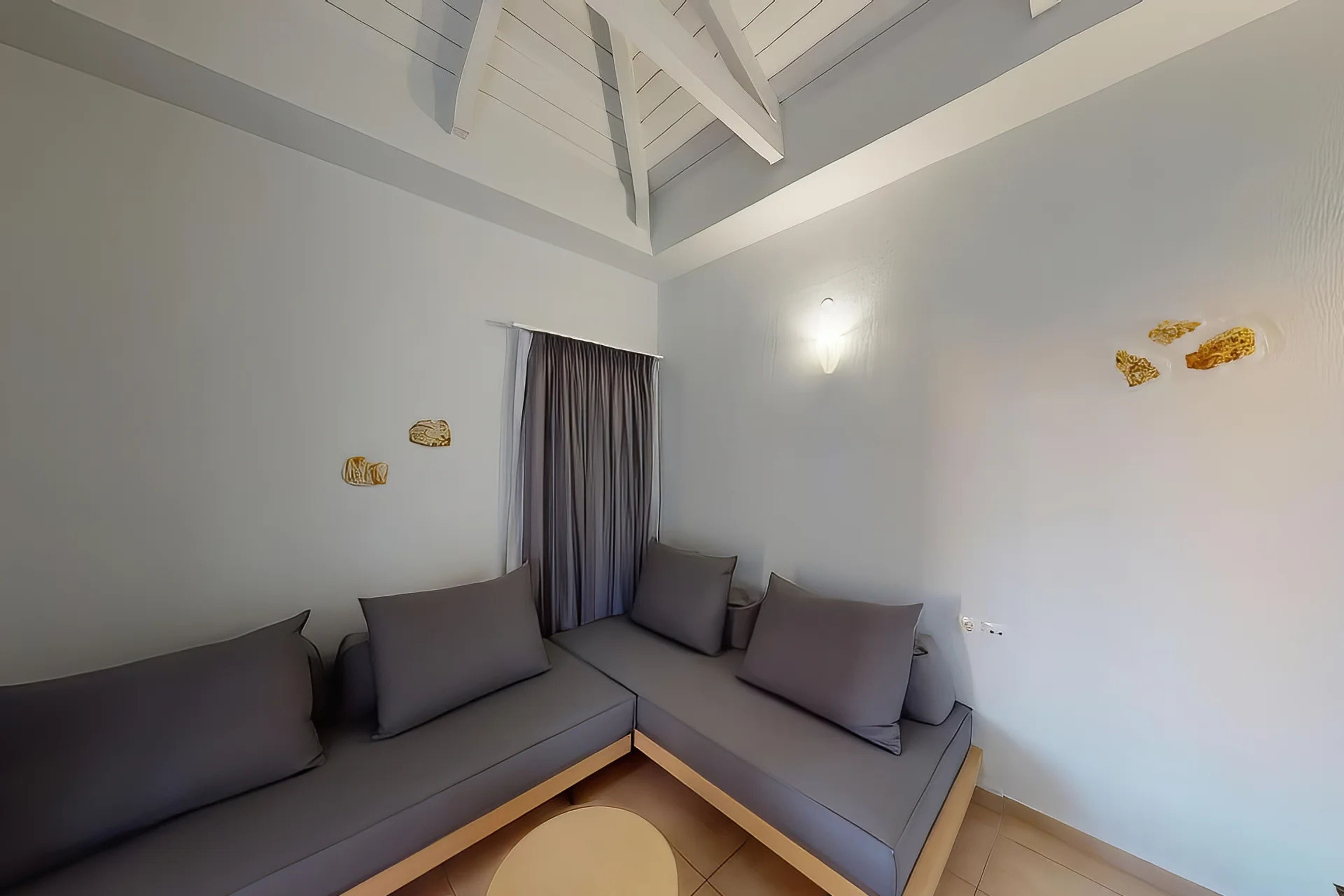 Una sala de estar moderna con un sofá modular, un ventilador de techo y una ventana con cortinas.