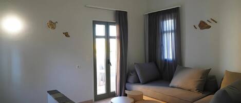 Una sala de estar moderna con un sofá, dos mesas redondas auxiliares, una escalera y un gran ventanal corredizo que da al exterior.