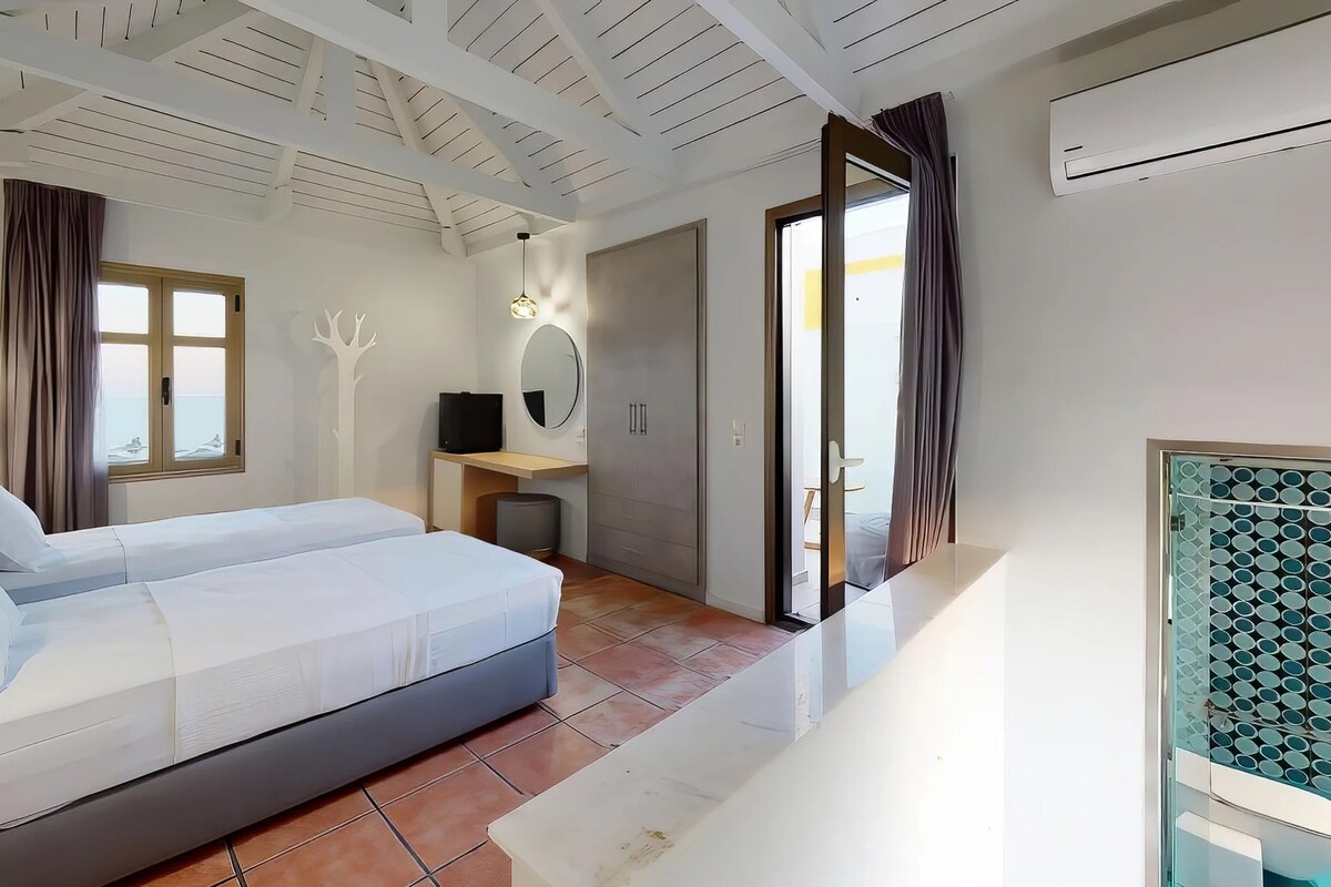 Un dormitorio con cama, escritorio, espejo y puerta corrediza a un balcón.