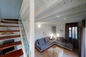Una sala de estar moderna con un sofá, una escalera de cristal y un televisor de pantalla plana.