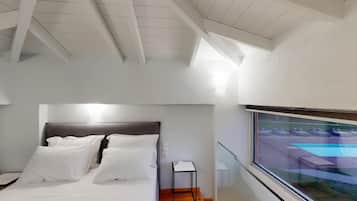 Un dormitorio moderno con cama, mesita de noche y ventana con vistas a una piscina.