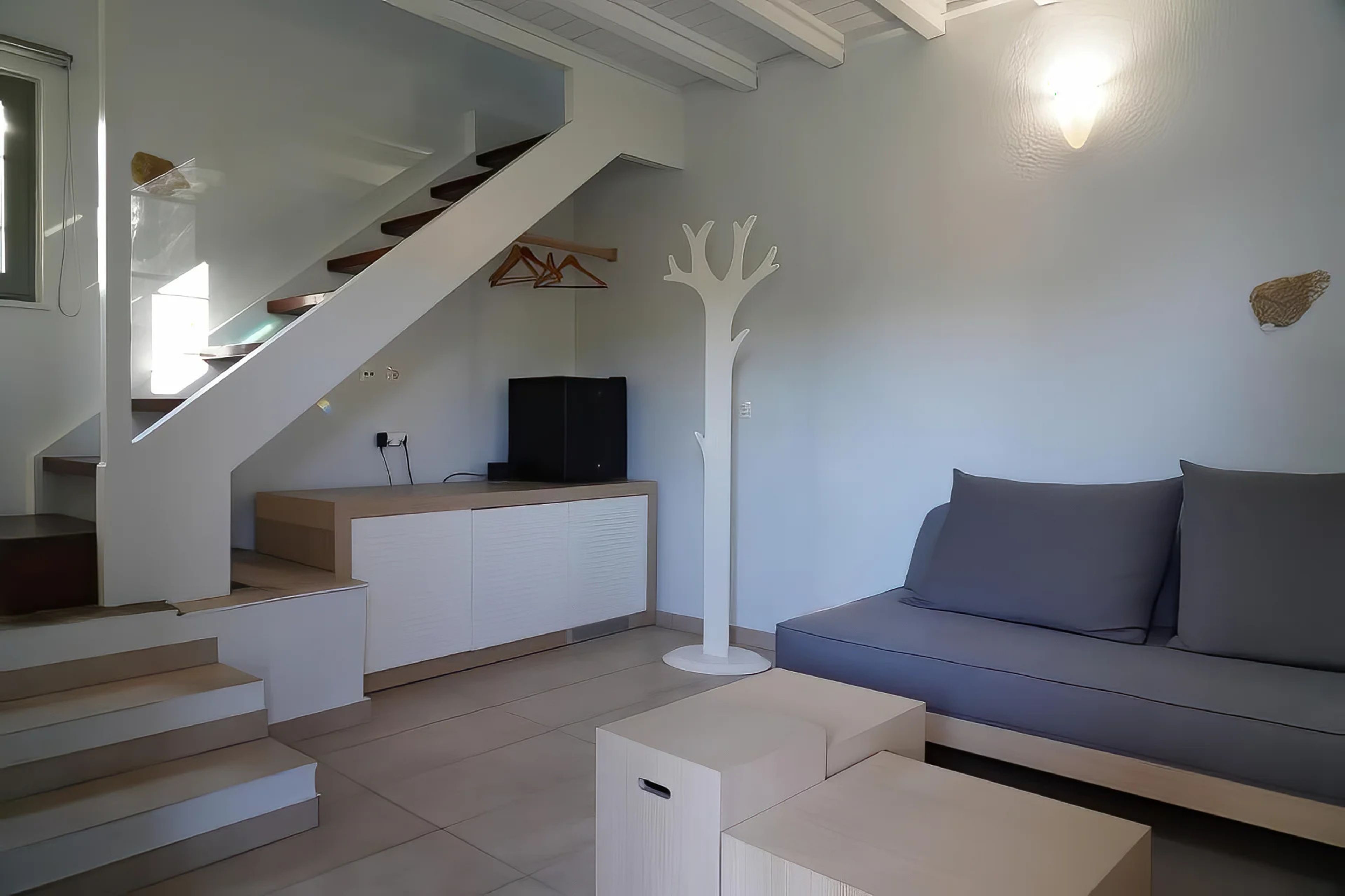 Una sala de estar moderna con una escalera, un sofá y un televisor de pantalla plana.