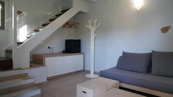 Una sala de estar moderna con una escalera, un sofá y un televisor de pantalla plana.