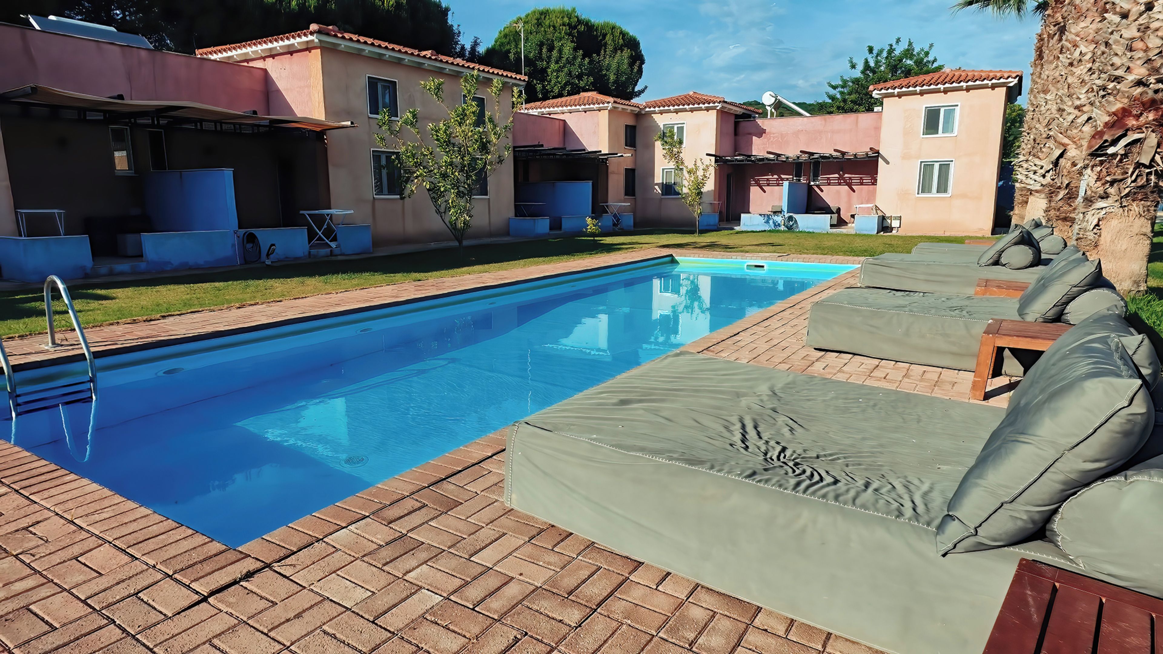 A swimming pool with lounge chairs and a brick patio.