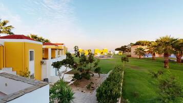 Una zona residencial con edificios de color amarillo y blanco, un césped cuidado y palmeras.