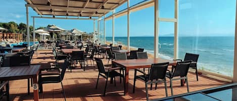 An outdoor seating area with tables and chairs, overlooking the ocean.