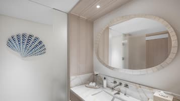 Un baño moderno con lavamanos de mármol, un espejo grande y una pieza decorativa de arte en la pared con forma de concha.