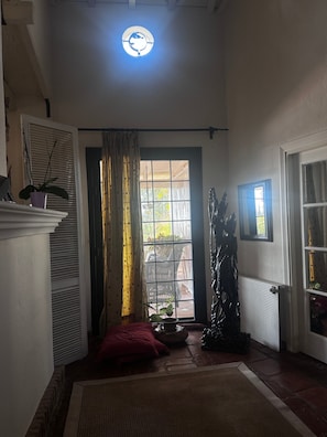 Ein Zimmer mit großem Fenster, Heizkörper, Topfpflanze und Deckenleuchte.