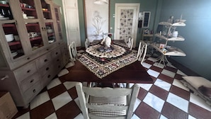 A dining room with a checkered floor, a large wooden cabinet with glass doors, and a patterned tablecloth. - Luxury Villa with All Amenities in Marbella – Pool, Jacuzzi, Barbecue, Wood-Fired Oven (Benahavís)
