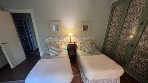 A room with two beds, a nightstand, a lamp, and a wardrobe. - Luxury Villa with All Amenities in Marbella – Pool, Jacuzzi, Barbecue, Wood-Fired Oven (Benahavís)