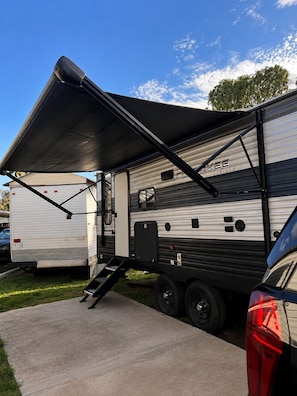 A recreational vehicle with a covered sleeping area, a kitchen section, and a storage compartment.