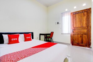 A hotel room with a bed, a desk, a chair, a wooden door, and a window. - Oyo 94249 Joglo Sorogenen (Kalasan)