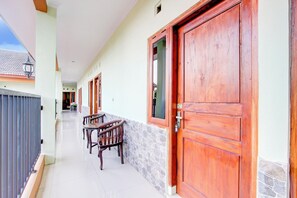 Un pasillo con puertas de madera, una pared de piedra y un banco.