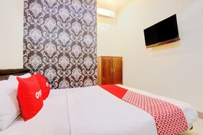 Una habitación de hotel con una cama, un armario, un televisor y un papel tapiz estampado.