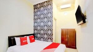Ein Hotelzimmer mit einem Bett, einem Schrank, einem Fernseher und einer Wand mit Muster.