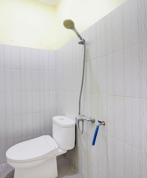 A bathroom with a toilet, a shower head, and a blue cleaning brush. - Oyo 94249 Joglo Sorogenen (Kalasan)