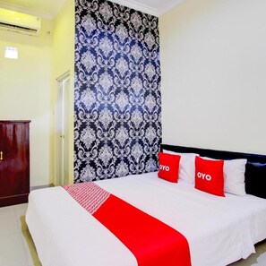 A hotel room with a bed, a wardrobe, and a patterned wall. - Hotel O Sleman Near Bandara Adi Sutjipto Formerly Joglo Sorogenen (Kalasan)