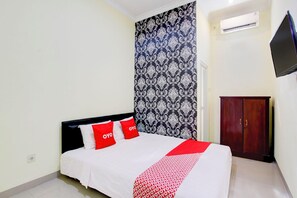 Une chambre à coucher comprenant un lit, une armoire, un téléviseur et un appareil de climatisation.