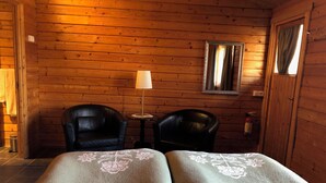 A wooden cabin room with two leather chairs, a small table, a lamp, and a mirror on the wall. - Vogafjós Farm Resort (Myvatn)