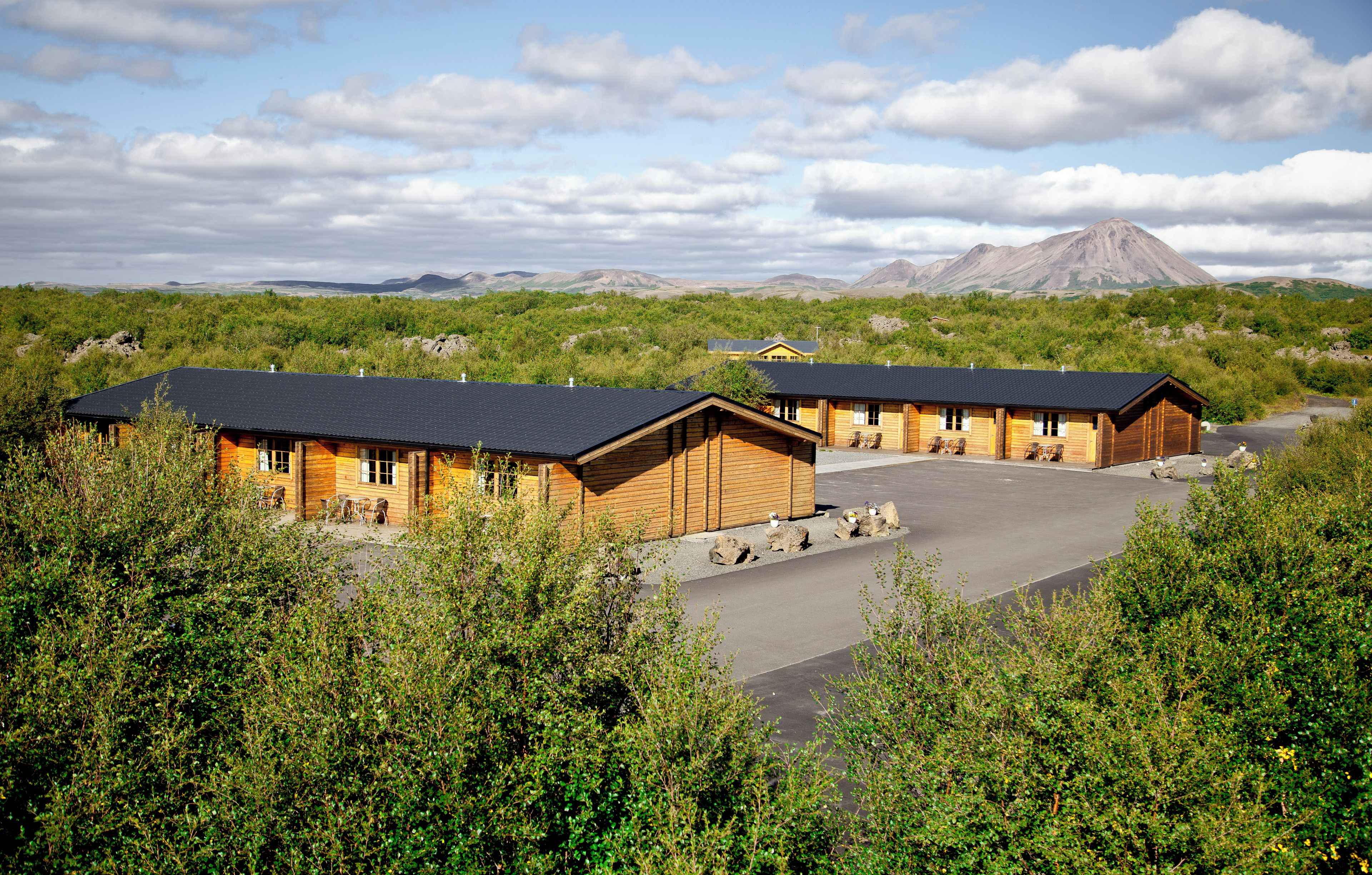 A lodge with multiple cabins, a paved driveway, and a mountainous backdrop.
