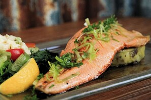 Un plato de salmón con vegetales y un gajo de limón.