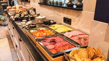 A buffet with various food items including meats, cheeses, and vegetables.