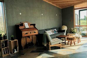 En moderne stue med et klaver, sofa og en lille skammel.