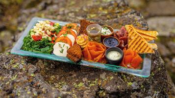 A food platter on a rock with various items including a salad, bread, and dips.
