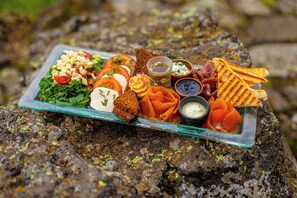 A food platter on a rock with various items including a salad, bread, and dips. - Vogafjós Farm Resort (Myvatn)