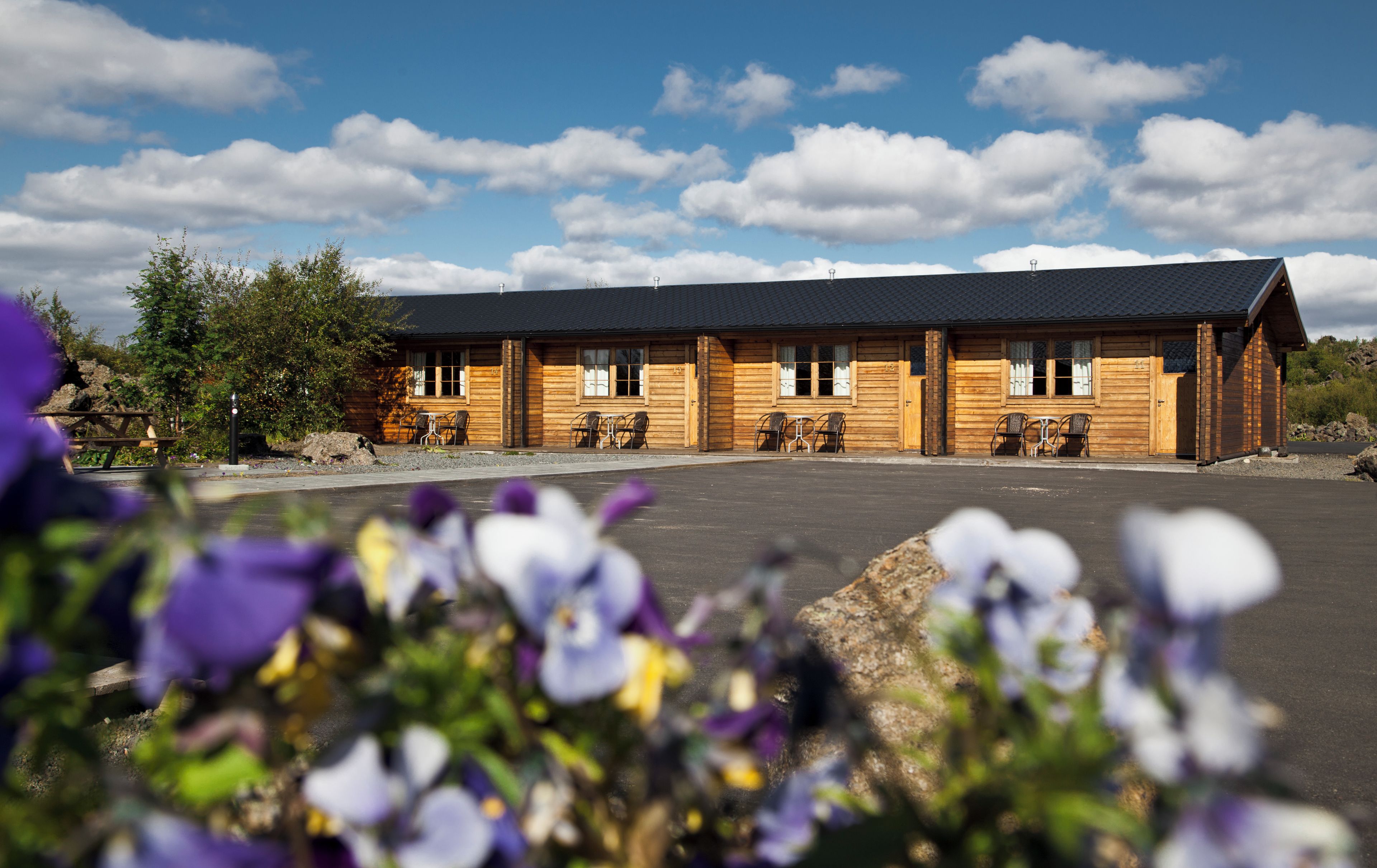 A wooden lodge with a flat roof, multiple windows, and outdoor seating.