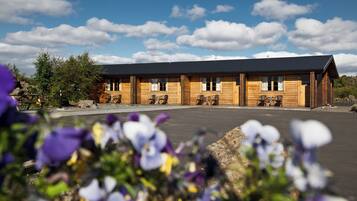 A wooden lodge with a flat roof, multiple windows, and outdoor seating.