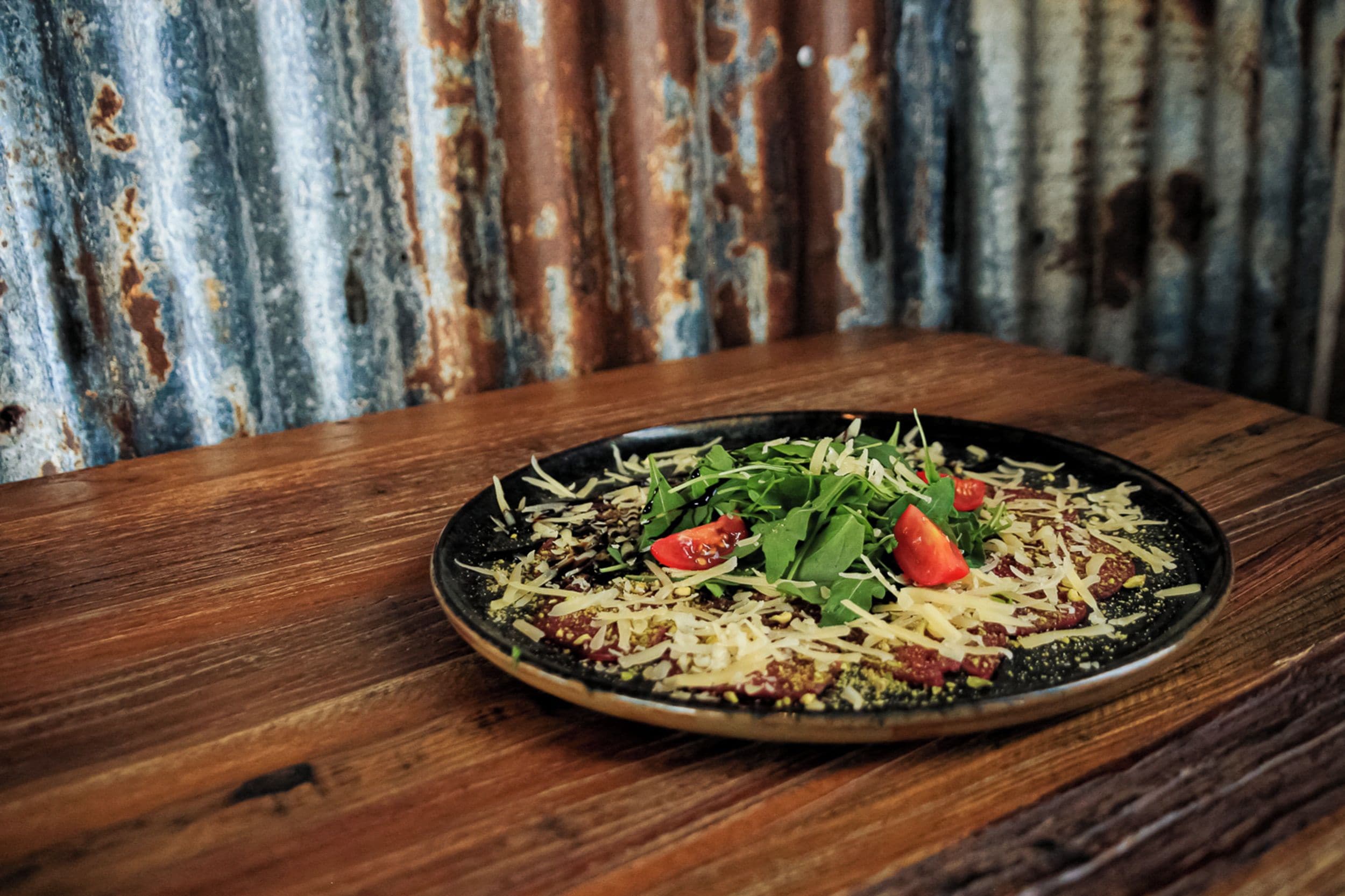 A plate of food on a wooden table with a corrugated metal background.