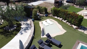 Un patio trasero con piscina, sillas de descanso y una pequeña terraza.