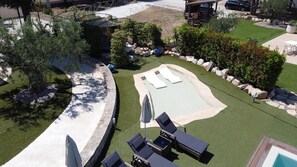Un jardin avec une piscine, des chaises longues et un petit espace aménagé en terrasse.