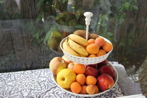 Obstauslage mit Bananen, Äpfeln und Pfirsichen auf einer gemusterten Tischdecke.
