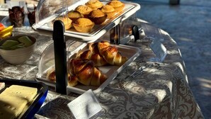 Un bufé de desayuno con bollería y vistas a la piscina.