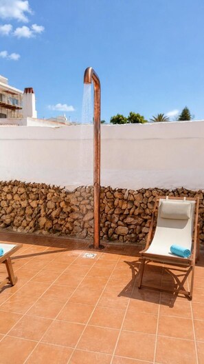 Una terraza en la azotea con un muro de piedra, un elemento decorativo de agua y dos sillones de descanso.