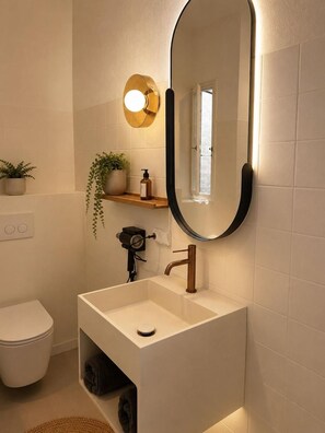 A modern bathroom with a white sink, a round mirror, and a toilet. - Hostal S Algaret (Mercadal)