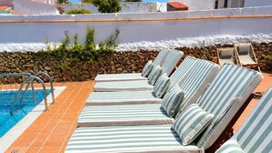 A row of sun loungers with striped cushions by a poolside. - Hostal S Algaret (Mercadal)