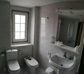 Baño con inodoro, bidé, lavamanos y ventana.
