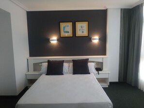 Ein Hotelzimmer mit einem großen Bett, zwei Nachttischen, einer Ablagefläche und zwei Wandlampen.