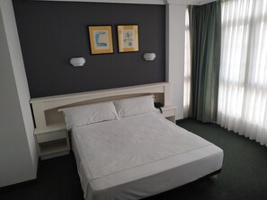 Ein Hotelzimmer mit Bett, Nachttischen, Kopfteil und zwei Wandlampen.